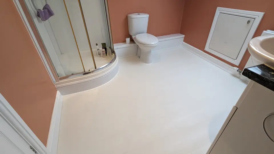 Loft bathroom with new light laminate flooring and terracotta walls