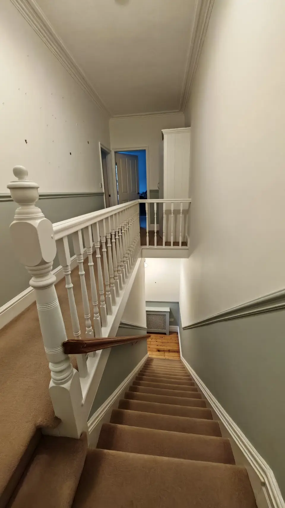 Landing from the top of the stairs: grey-green below the dado, white gloss newel post and spindles