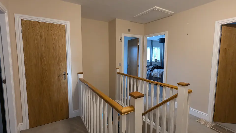 Landing decorated in a warm neutral with white spindles and oak doors