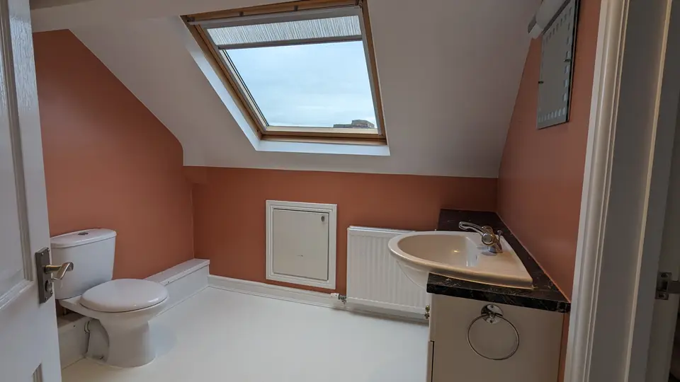 After: loft bathroom painted terracotta under the roof window