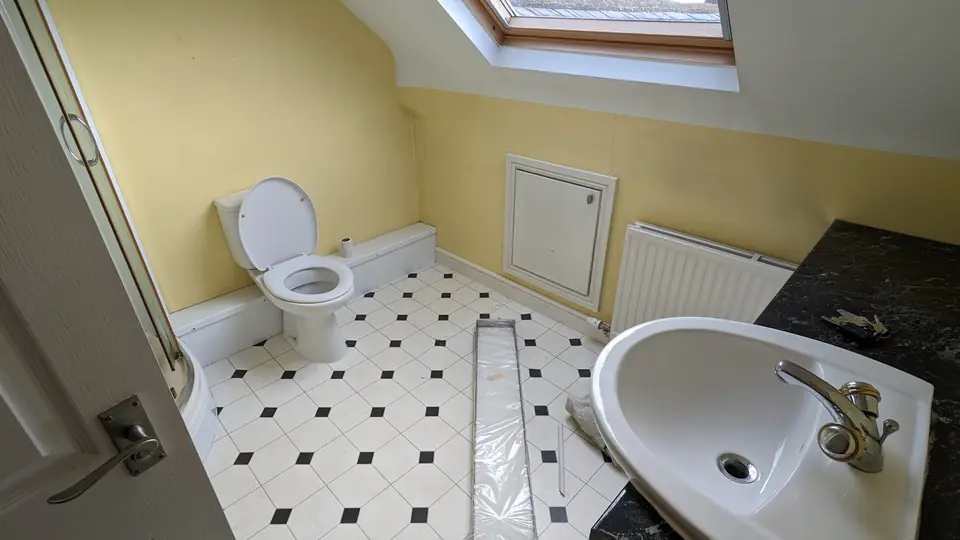 Before: loft bathroom with yellow walls and black and white floor