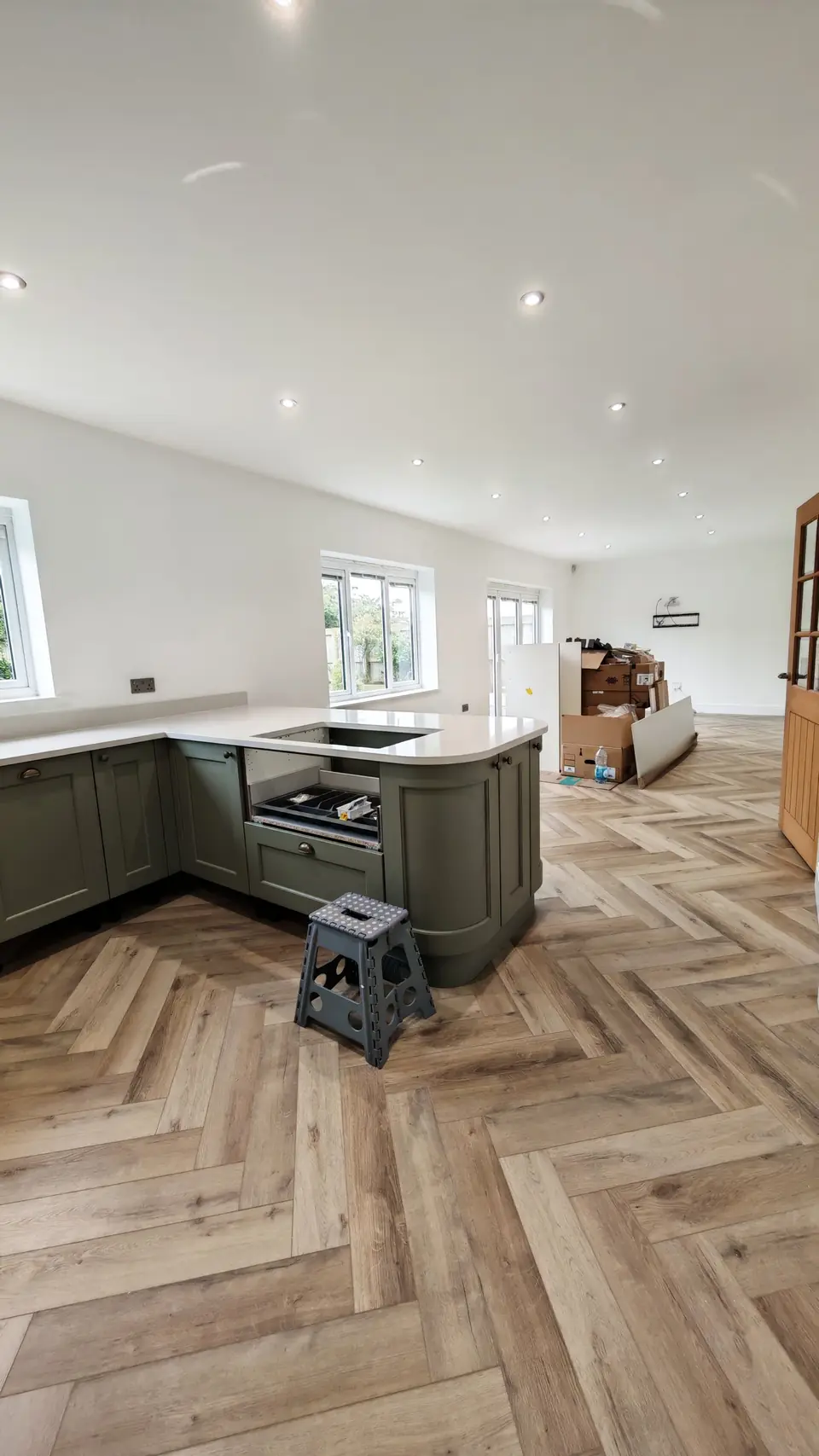 Oak herringbone LVT floor around a green kitchen island