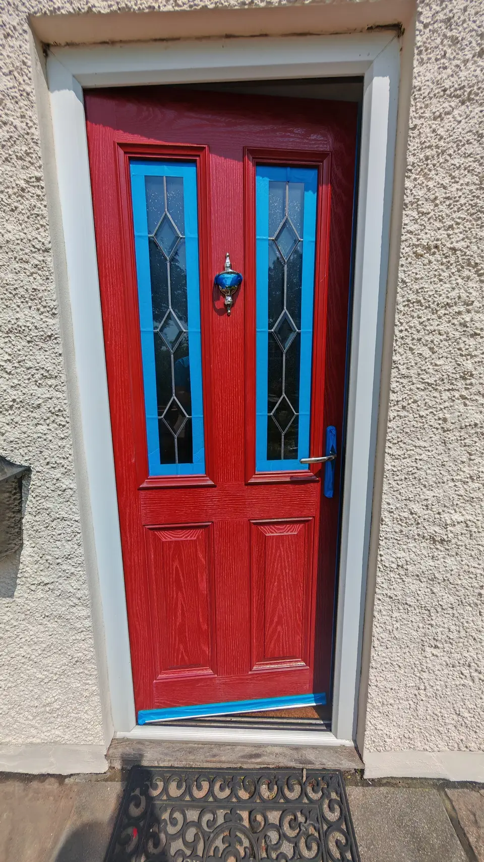 Before: red composite front door with stained glass, masked up for spraying