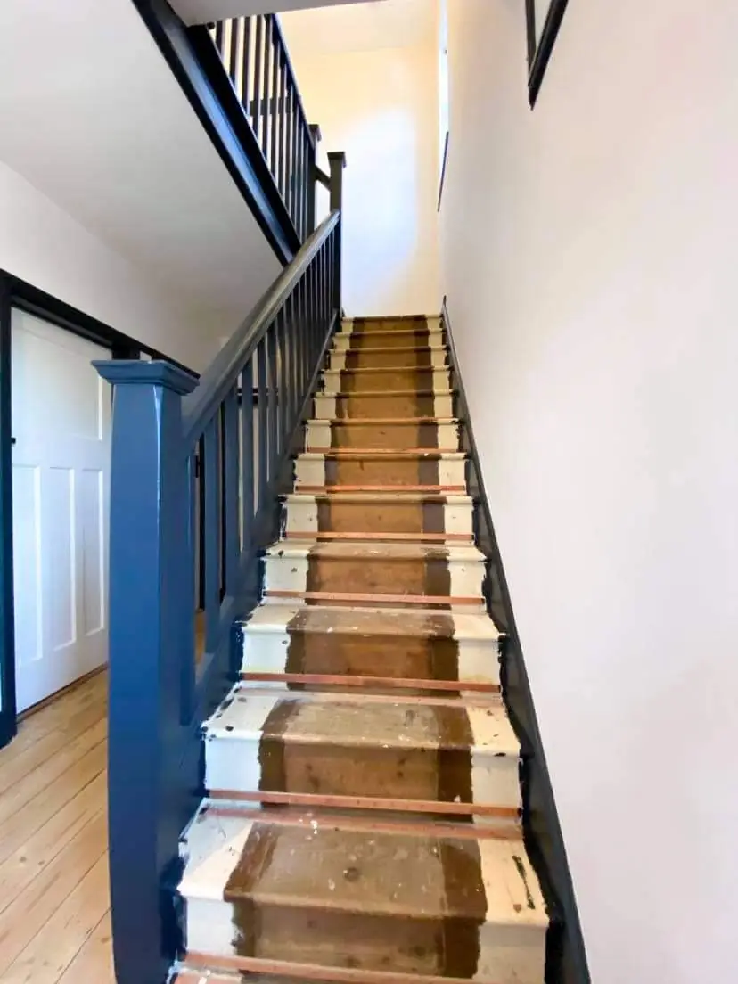 Staircase with navy painted spindles, handrail and newel post against white walls