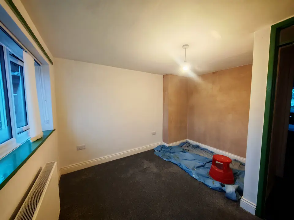 Room with new plaster on one wall and fresh paint on the others, ready for finishing coats