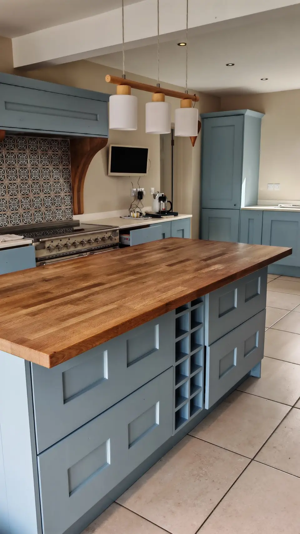 Oak shaker kitchen resprayed in soft blue: island with its oak top kept, range hood corbels in natural oak