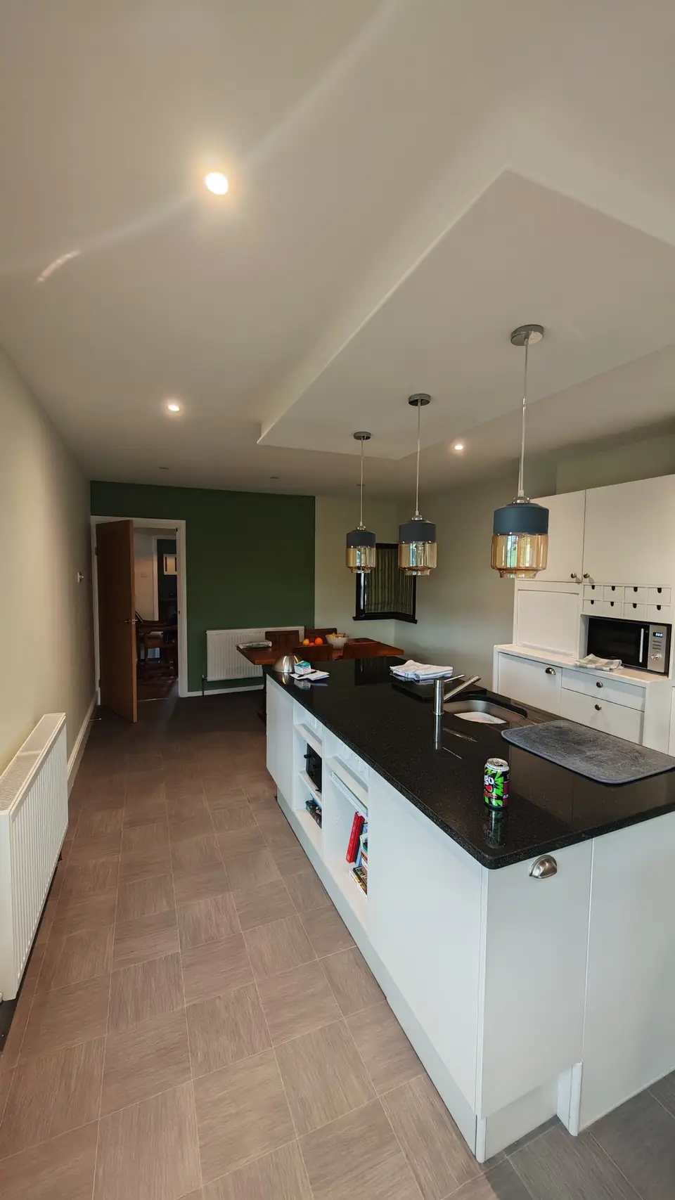 Kitchen island in front of the new green feature wall