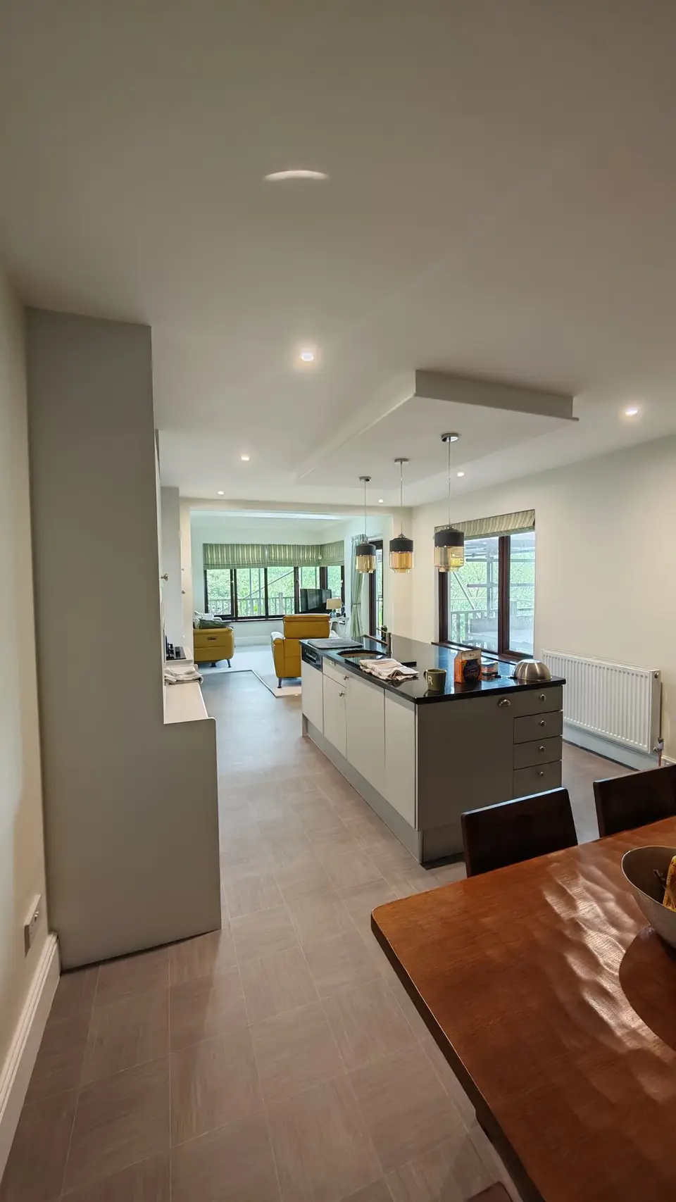 Open-plan kitchen and dining area repainted: white units with a green feature wall by the dining table