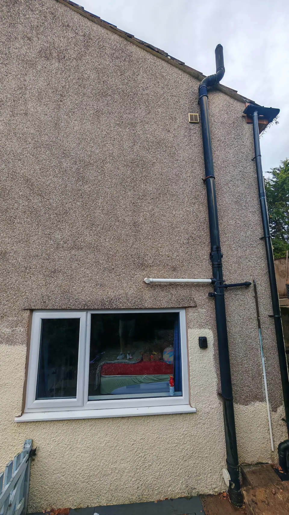 The difference in one photo: wall by the window and downpipe half painted in cream masonry paint