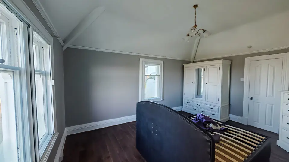 Bedroom with a vaulted ceiling, repainted in soft grey and white