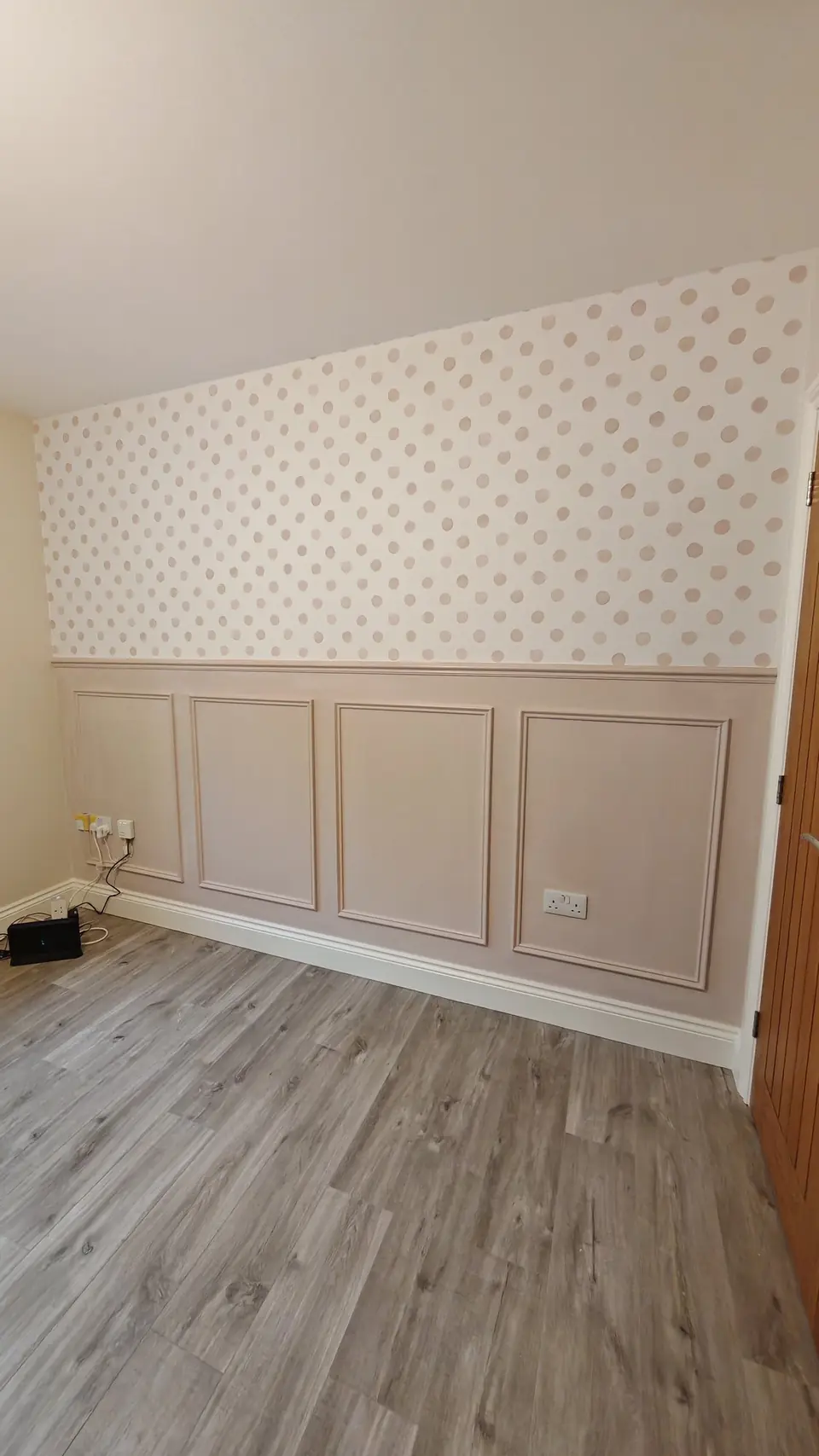 Pink painted panelling with polka dot wallpaper above the dado rail