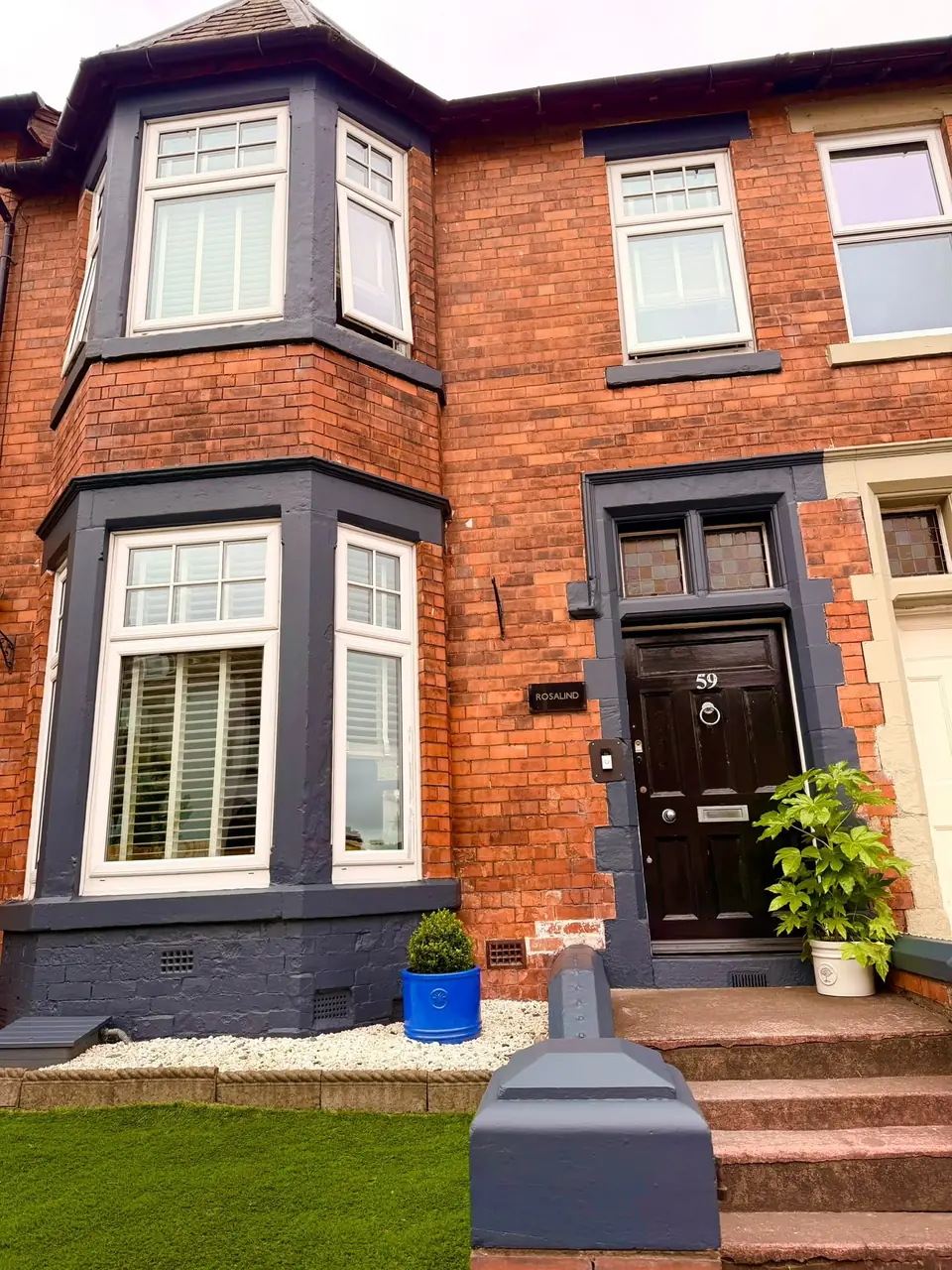 Victorian red-brick terrace: bay window surrounds, door surround and plinth painted dark grey-blue