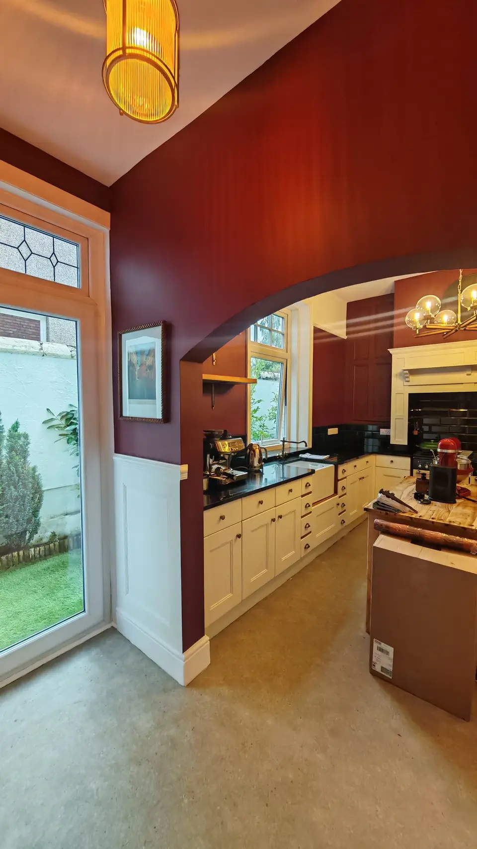 After: view through the arch into the redecorated kitchen, burgundy walls and resprayed cream cabinets