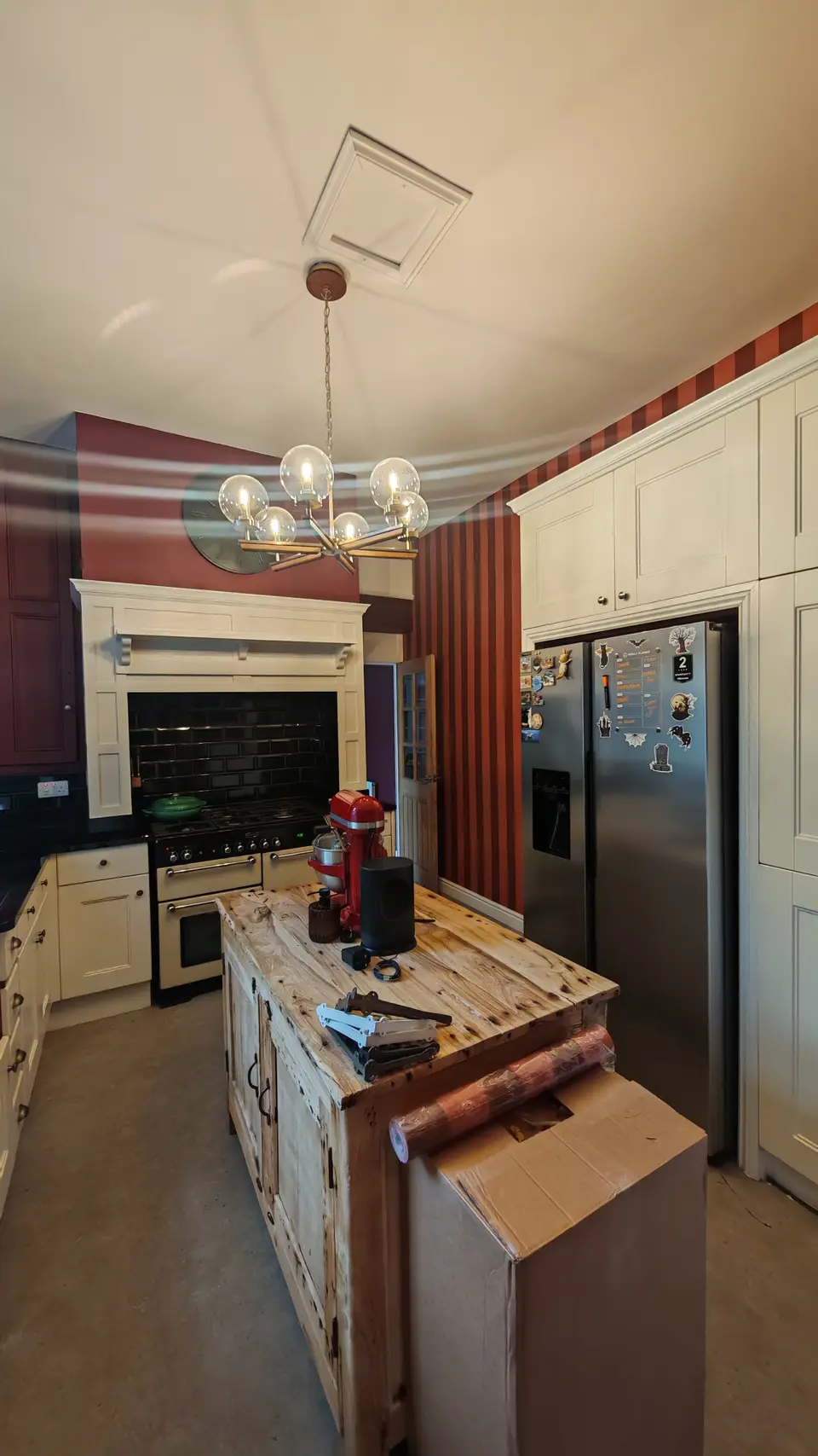 After: kitchen with striped wallpaper feature wall, burgundy walls and cream units