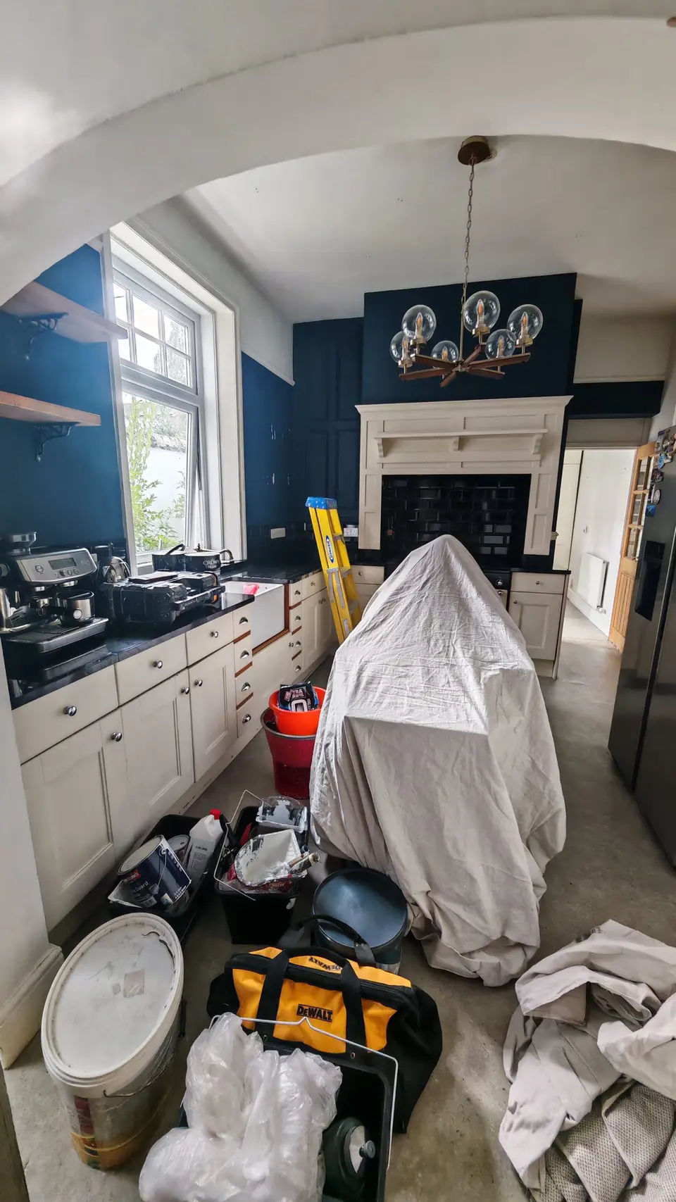 Before: navy blue kitchen through the arch, island under dust sheets