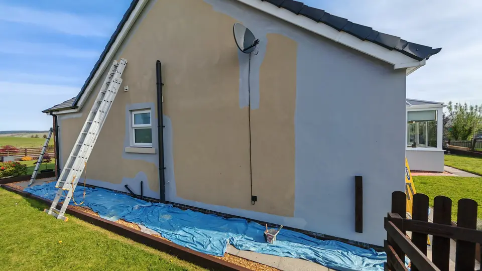 Before: bungalow side wall with patched render, ladder up