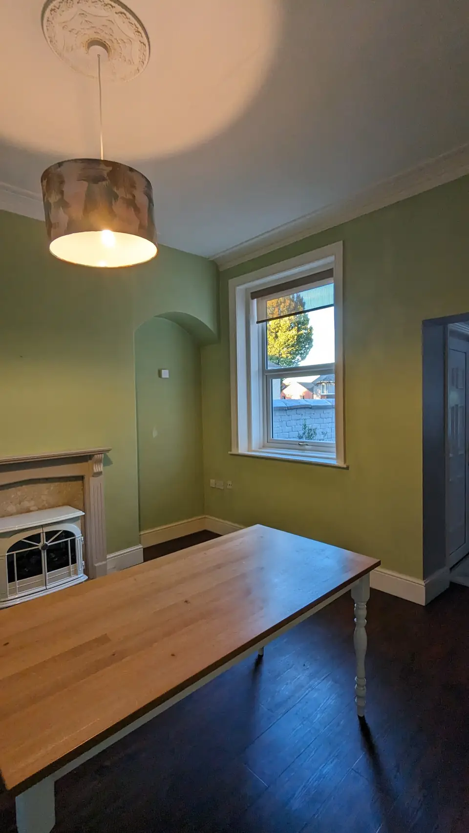 Sage green dining room with stone fireplace and oak table