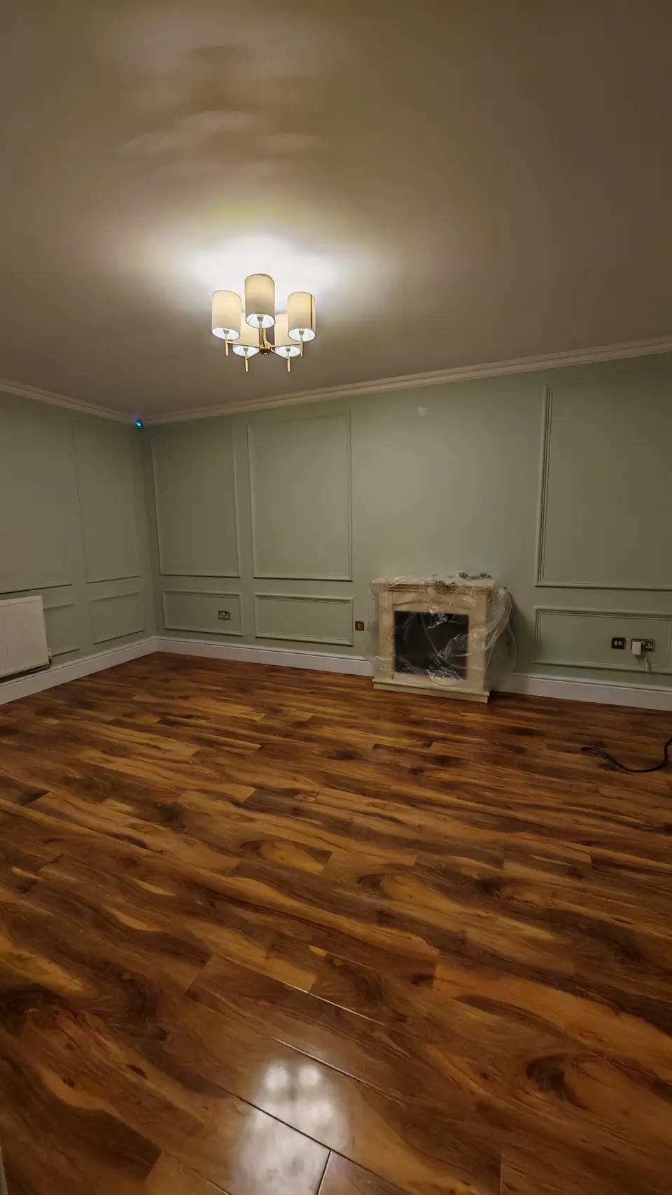 Room with box panelling painted sage green on every wall, with a white ceiling