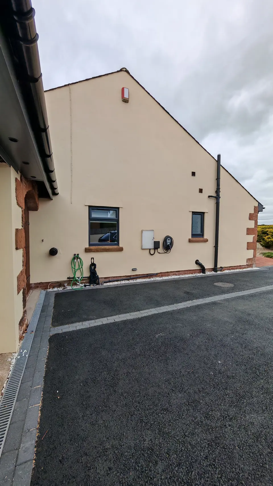 Gable wall in cream masonry paint, sandstone quoins at the corner