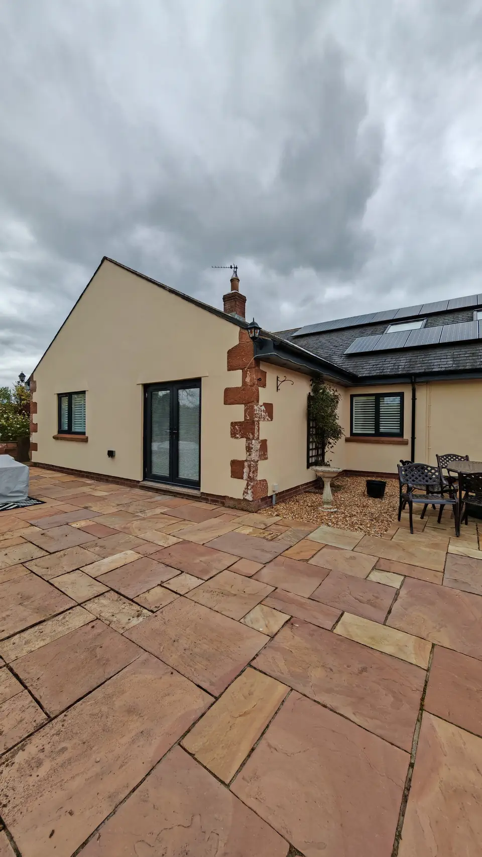 Cream render with red sandstone quoins: rear patio and French doors