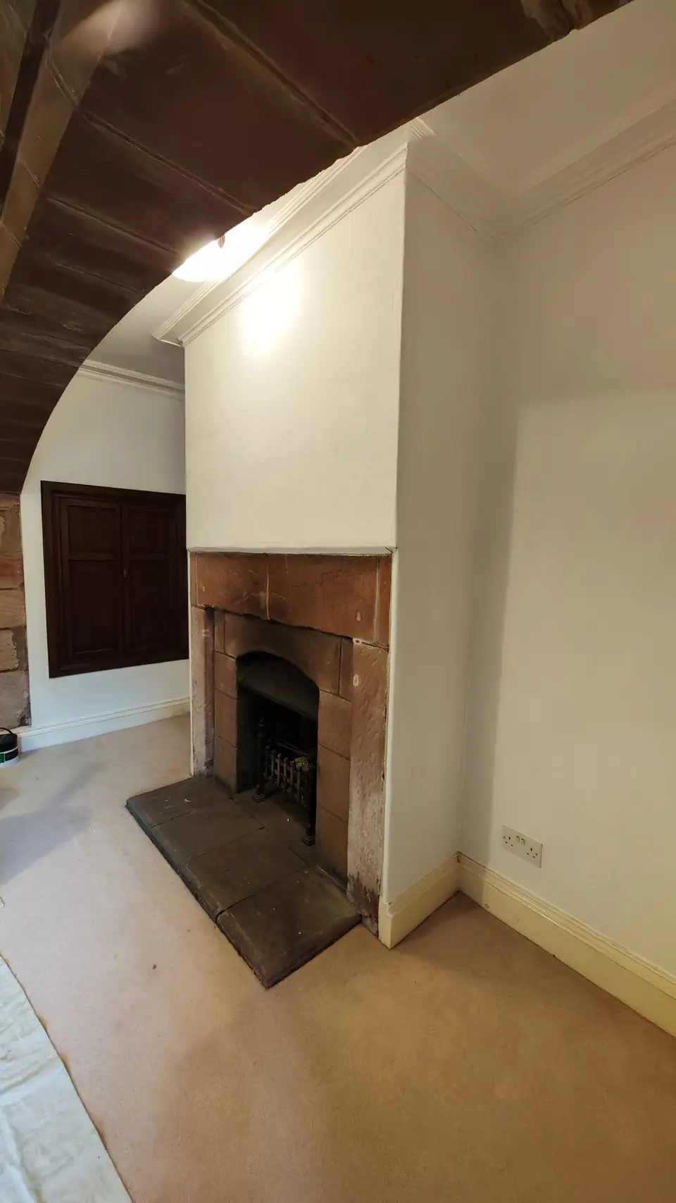 Chimney breast lined and painted white under the sandstone arch