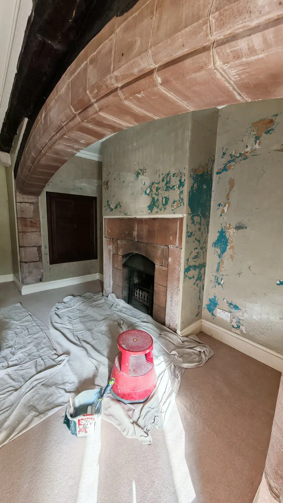 Before: damp chimney breast with flaking green paint under the sandstone arch