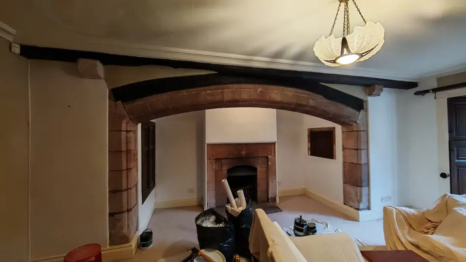The whole period room: sandstone arch, fireplace and beams with fresh white walls