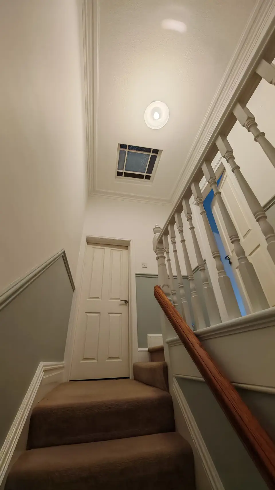 Top of the stairs under the skylight, freshly painted, mahogany handrail
