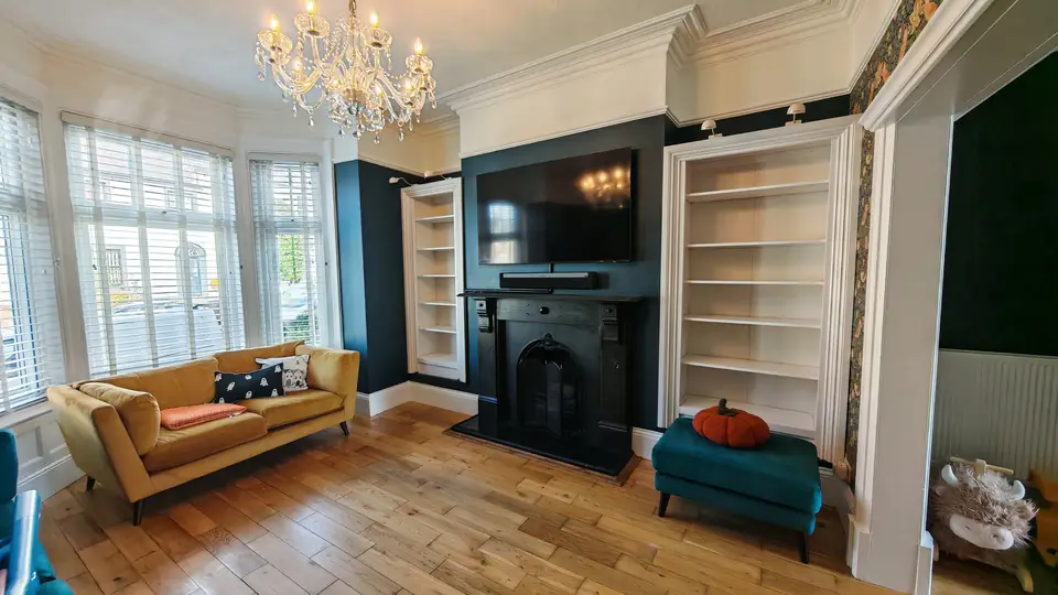 Dark teal living room with fireplace, alcove shelving and chandelier