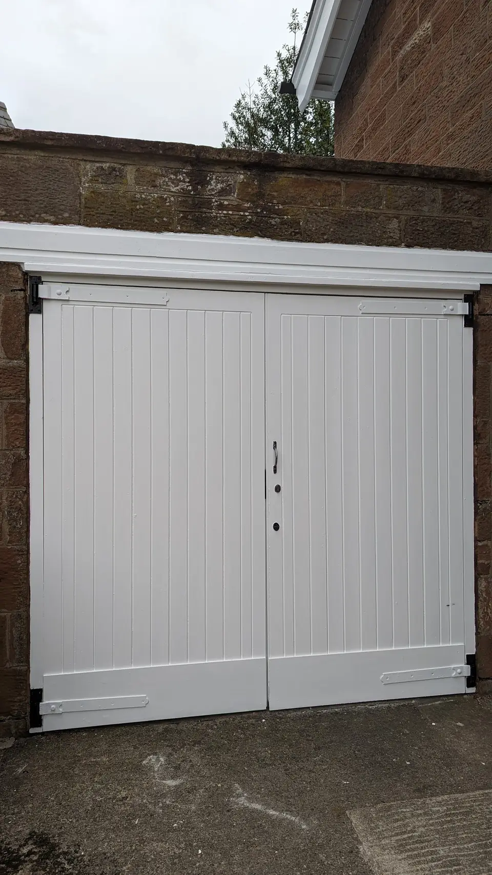 After: timber garage doors repaired and painted white