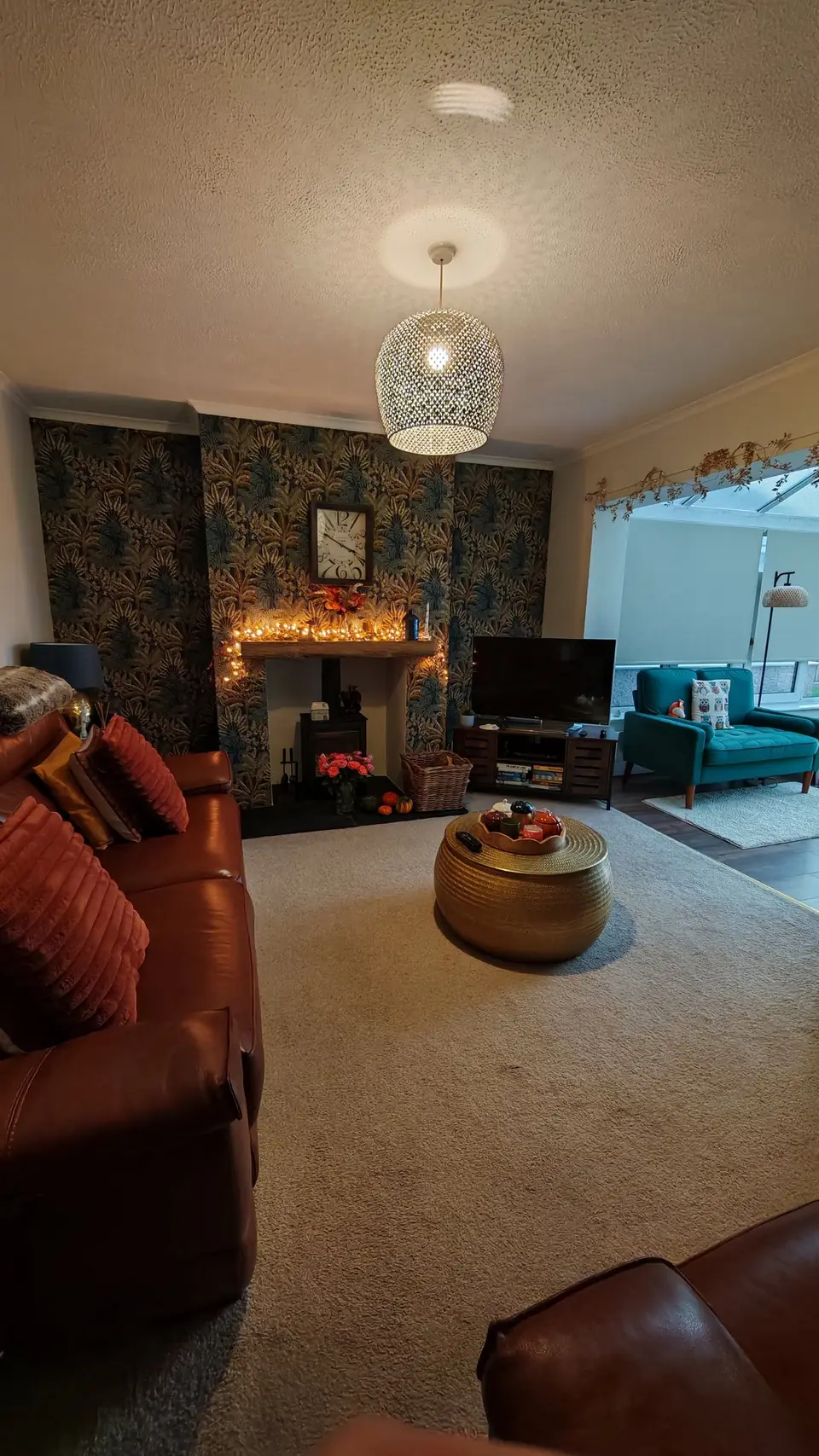 Styled lounge with the tropical wallpaper chimney breast and lamps lit