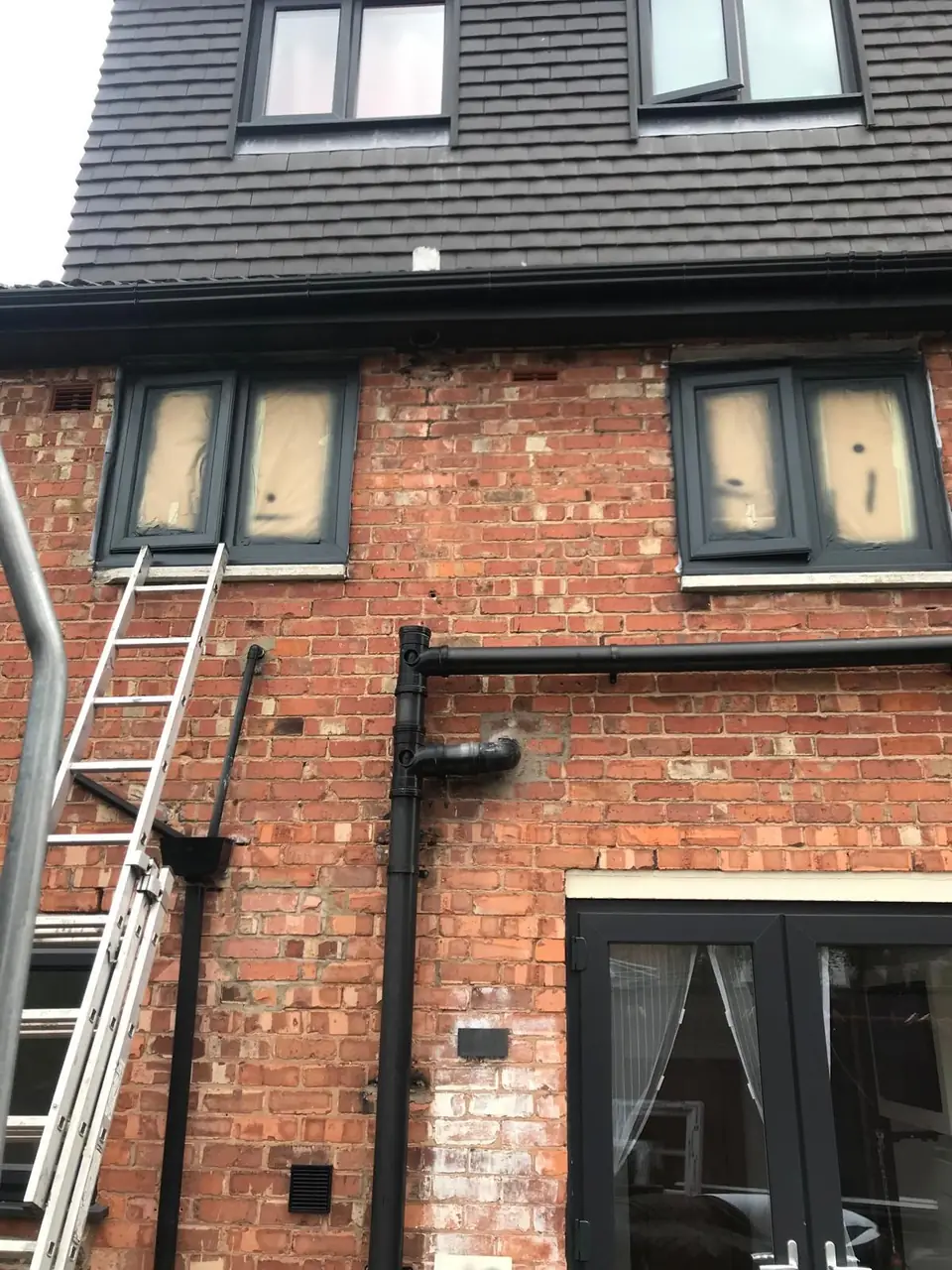 Anthracite UPVC windows on a brick house masked with paper and film, ready for spraying