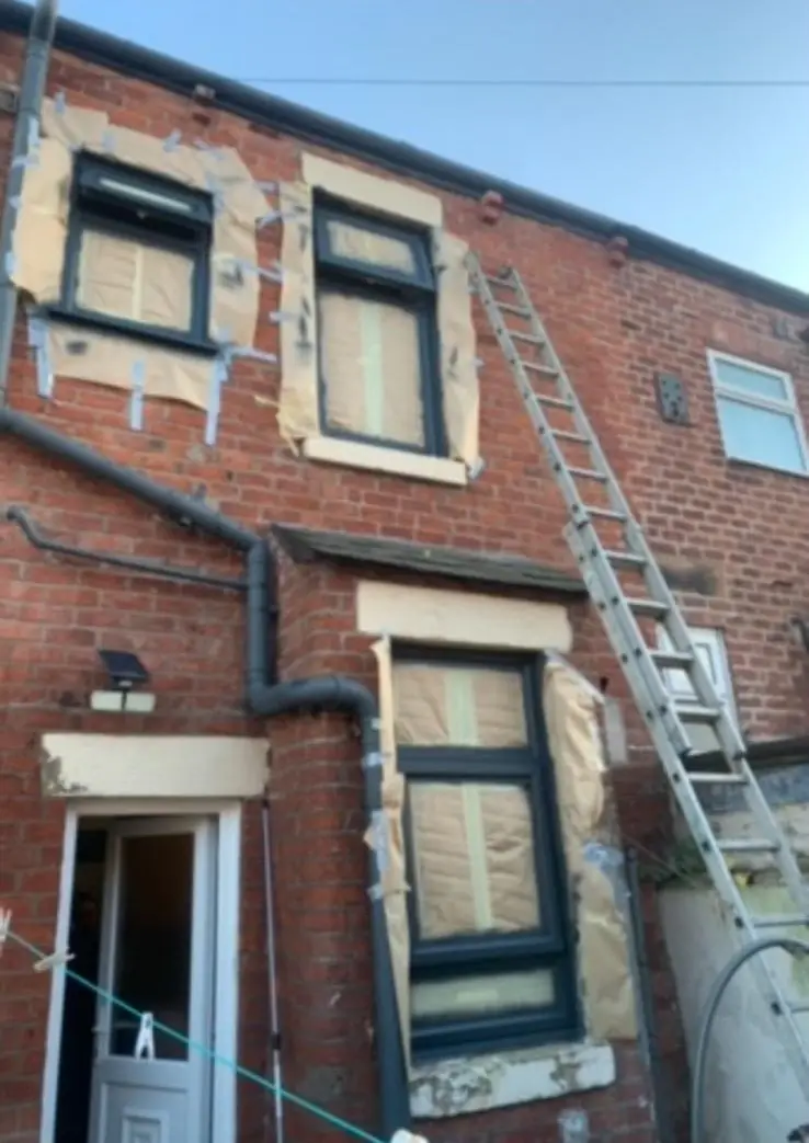 Rear of a brick house with UPVC windows masked up for spraying, ladder in place