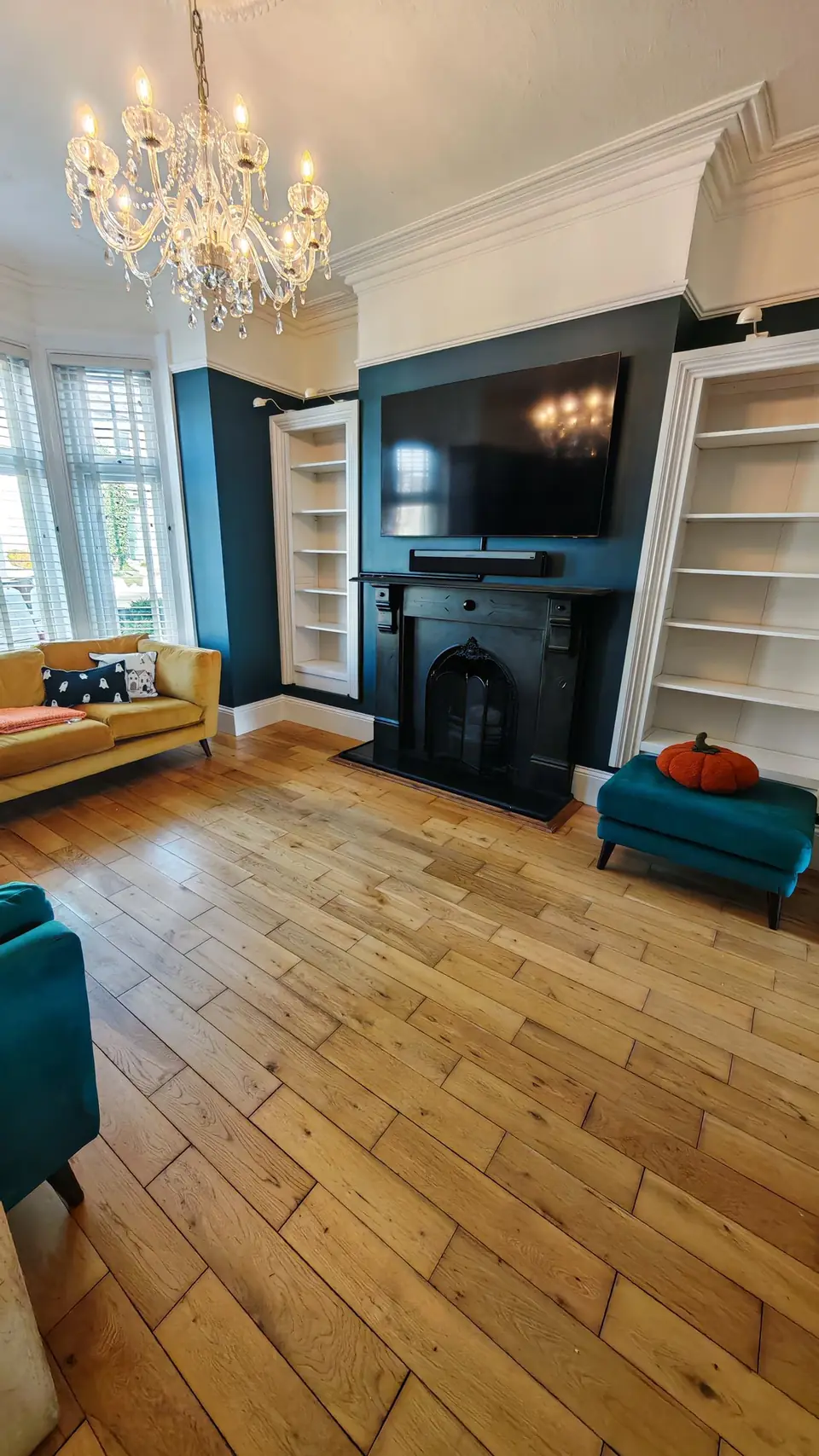 Lounge chimney breast and white alcove shelves against deep teal