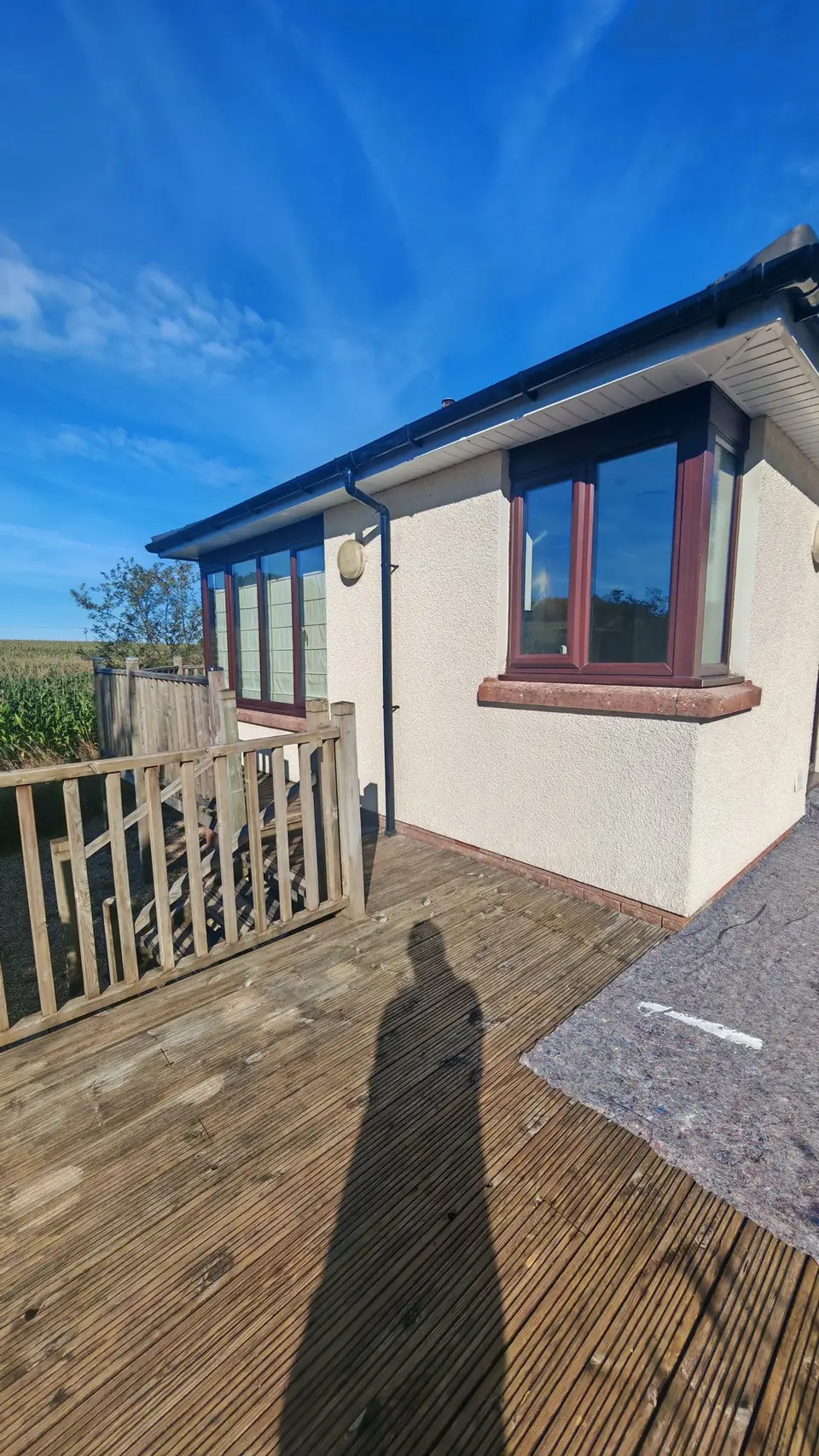 Before: cream render by the decking, dust sheets down