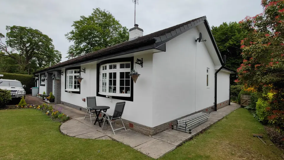 White-painted bungalow with crisp black window surrounds and a patio, after exterior painting
