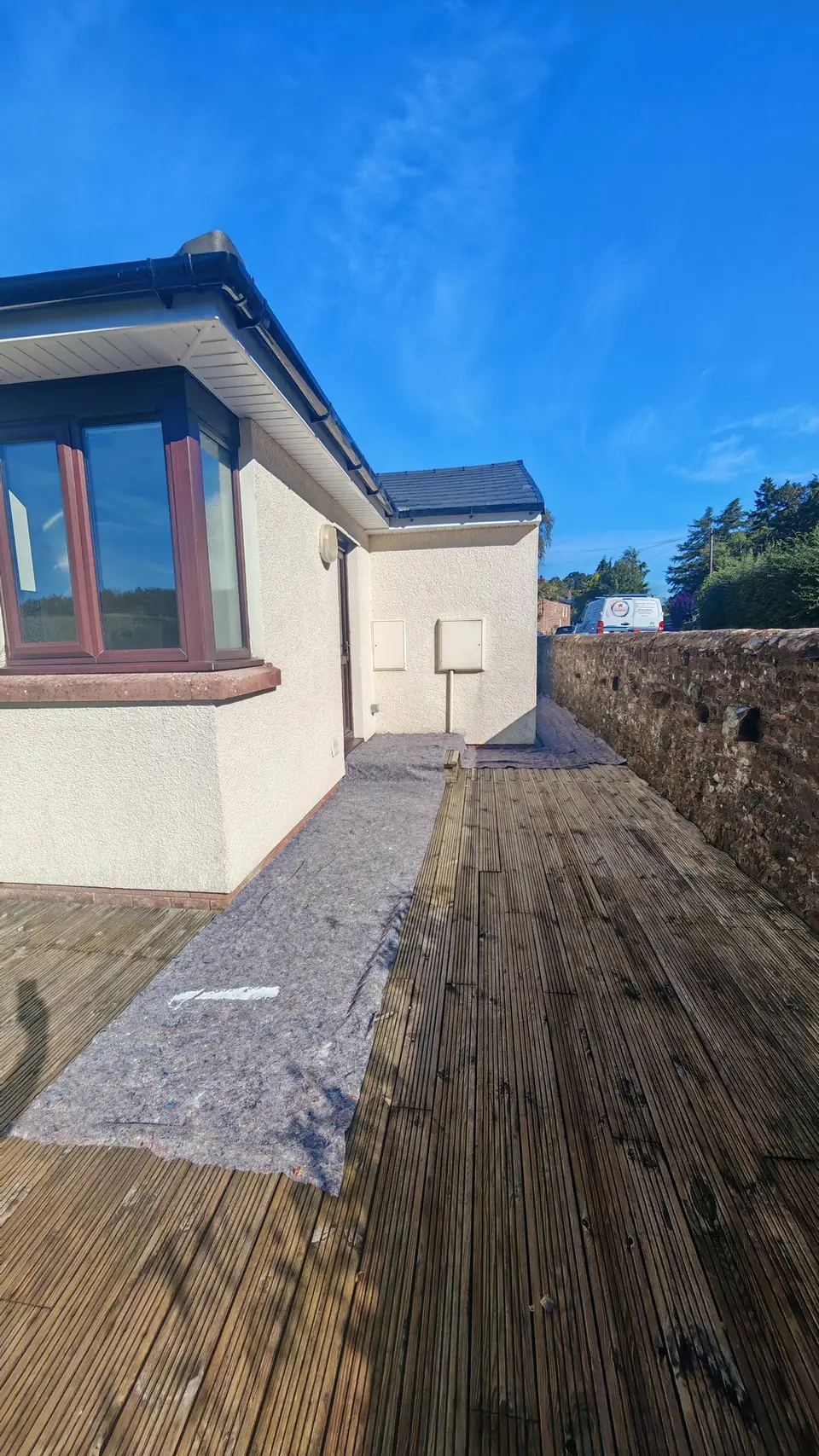 Before: side wall in cream with dust sheets on the decking