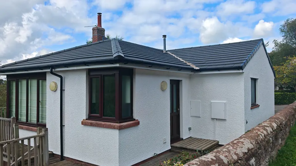Bungalow render painted white, with black downpipes and a red garage door