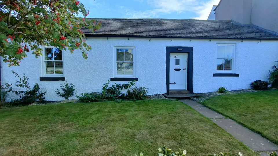 Long white-painted cottage with a black door surround and sills, after exterior painting