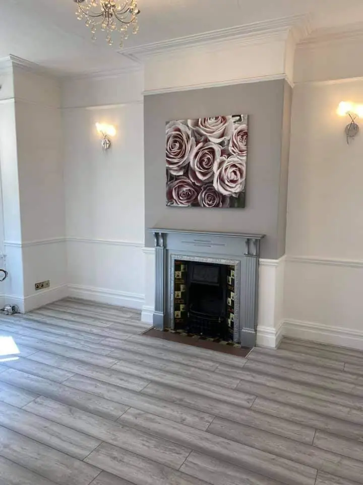 Bright white living room with a grey chimney breast, cast-iron fireplace and panelled walls