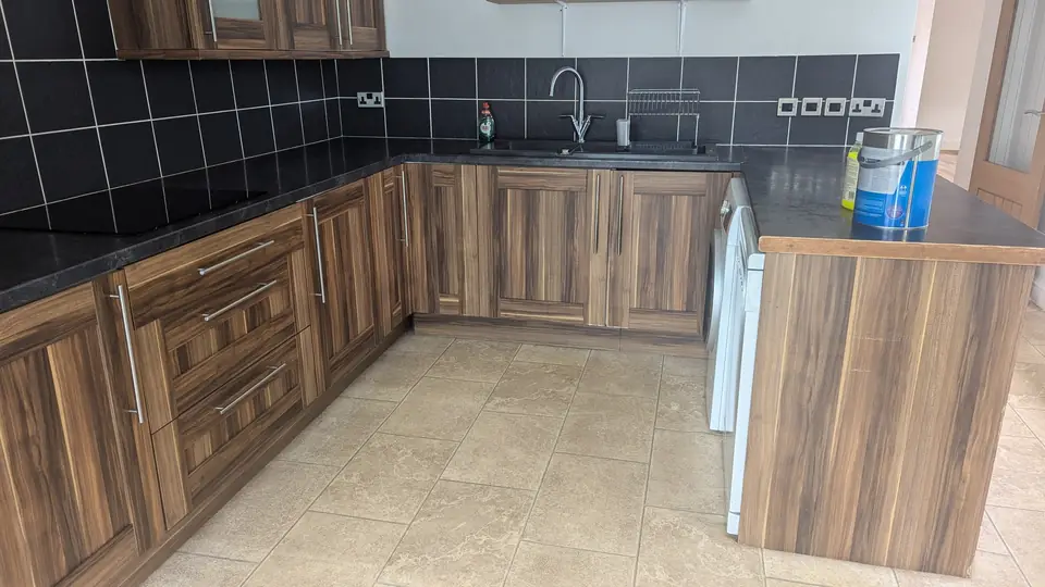 Before: dark woodgrain kitchen units and black tiled splashback