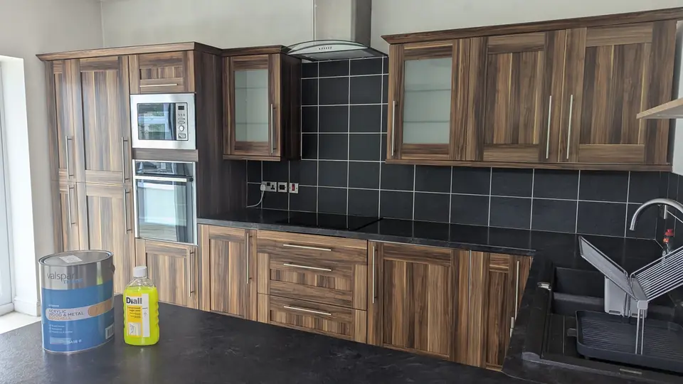 Before: woodgrain kitchen run with built-in ovens and hob